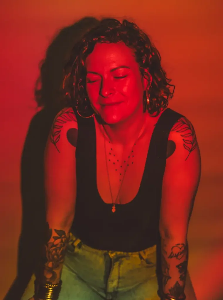 Femme tatouée éclairée en rouge, yeux fermés